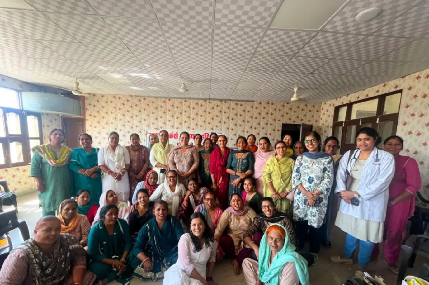 A group of health workers and community members gathered indoors for a HeatWatch safety discussion